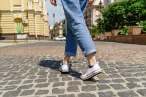 Close up of person walking on paving stone street at summer day.